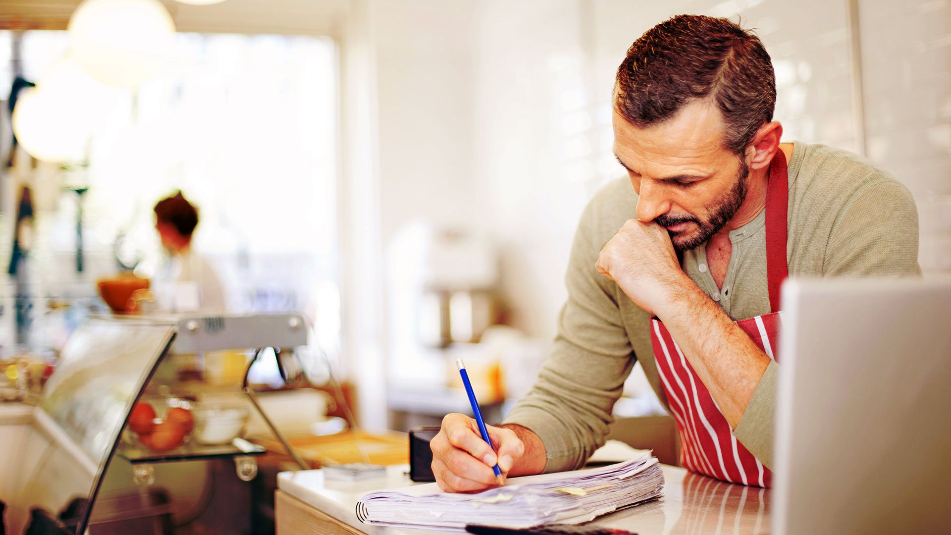 Male shop owner in apron doing paperwork